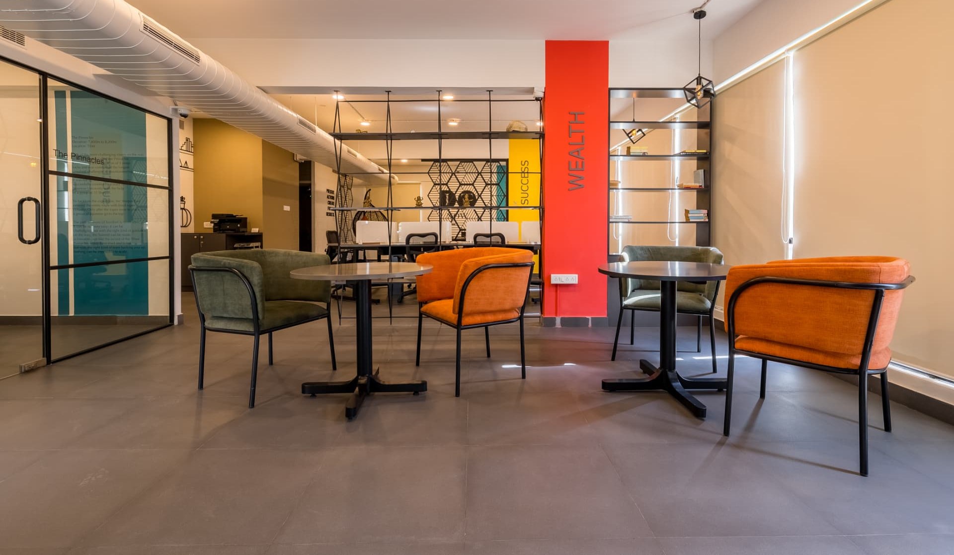 Second floor lounge with orange and green chairs beside open workstations