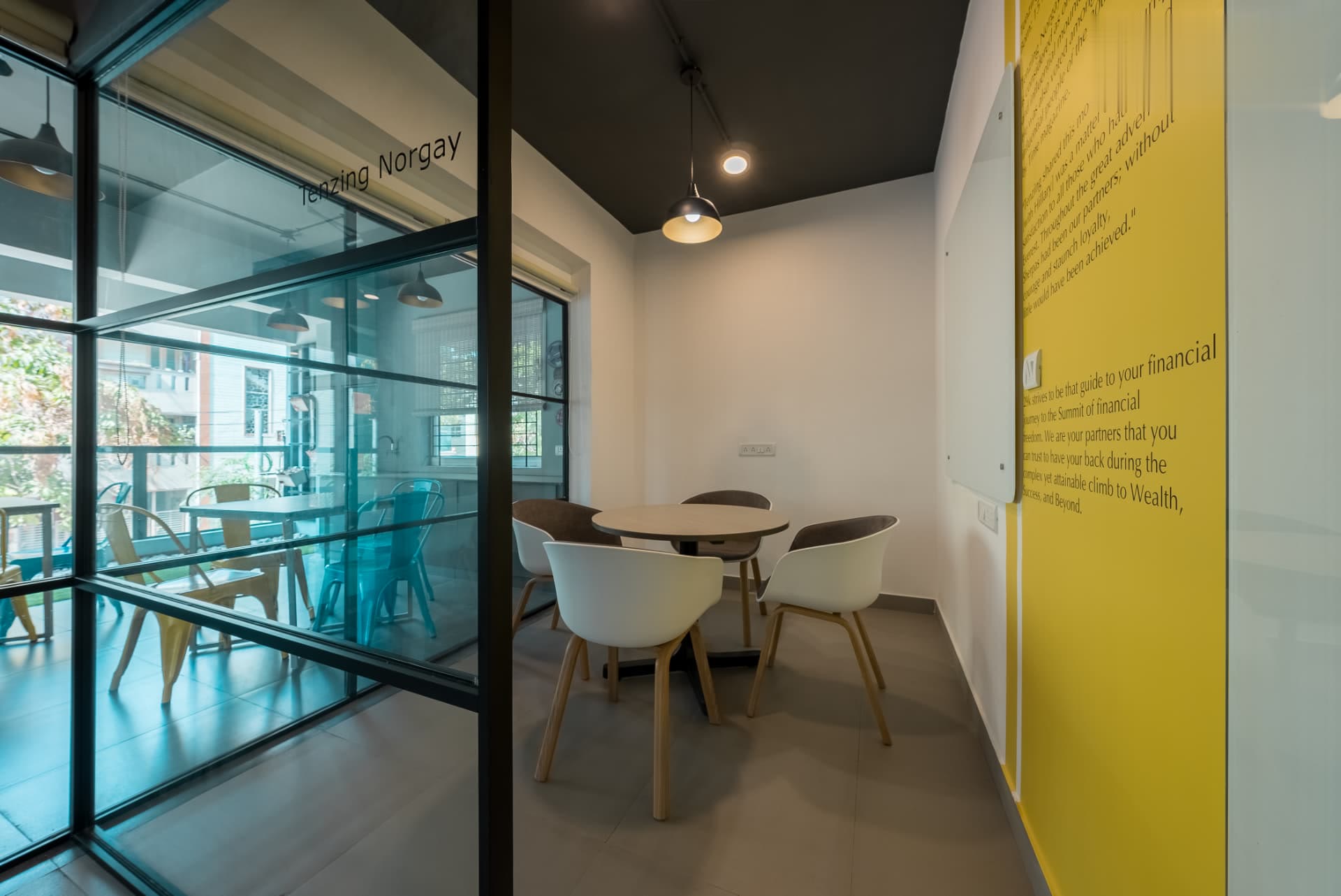 Tenzing Norgay meeting room with a round table, white chairs and a yellow feature wall