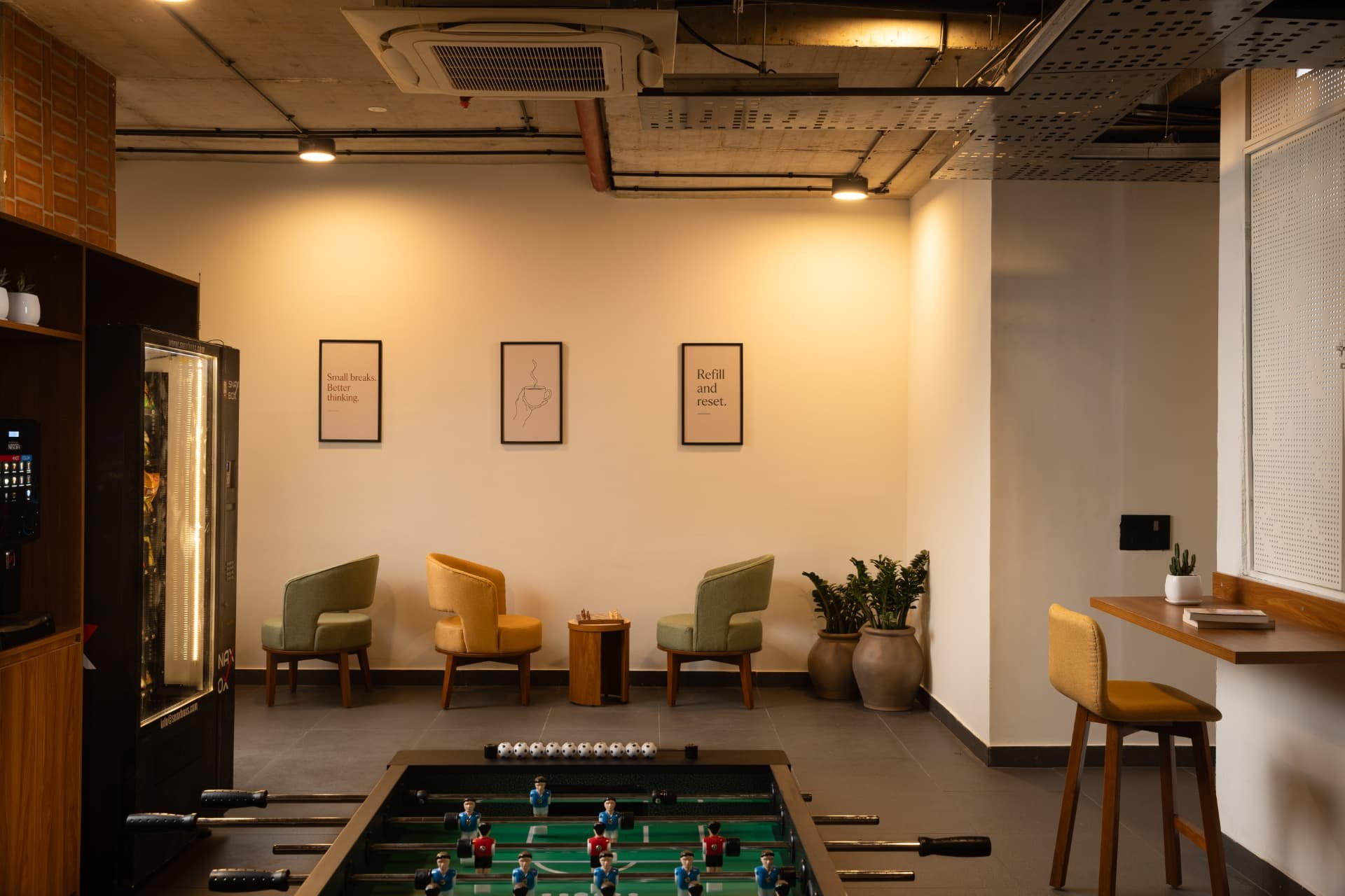 Common area at Steadwork with upholstered lounge chairs, framed prints and potted plants