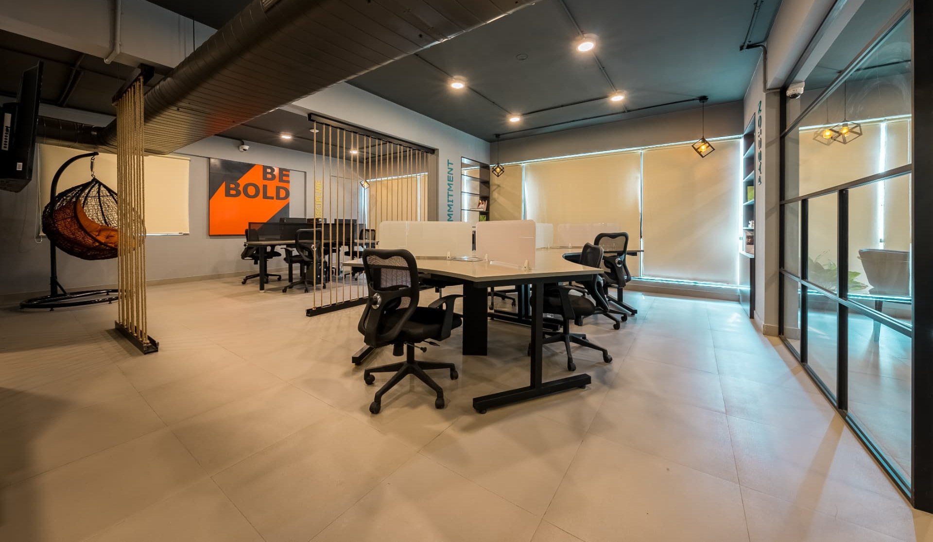 Open plan workstations on the first floor with acoustic screens and a hanging chair