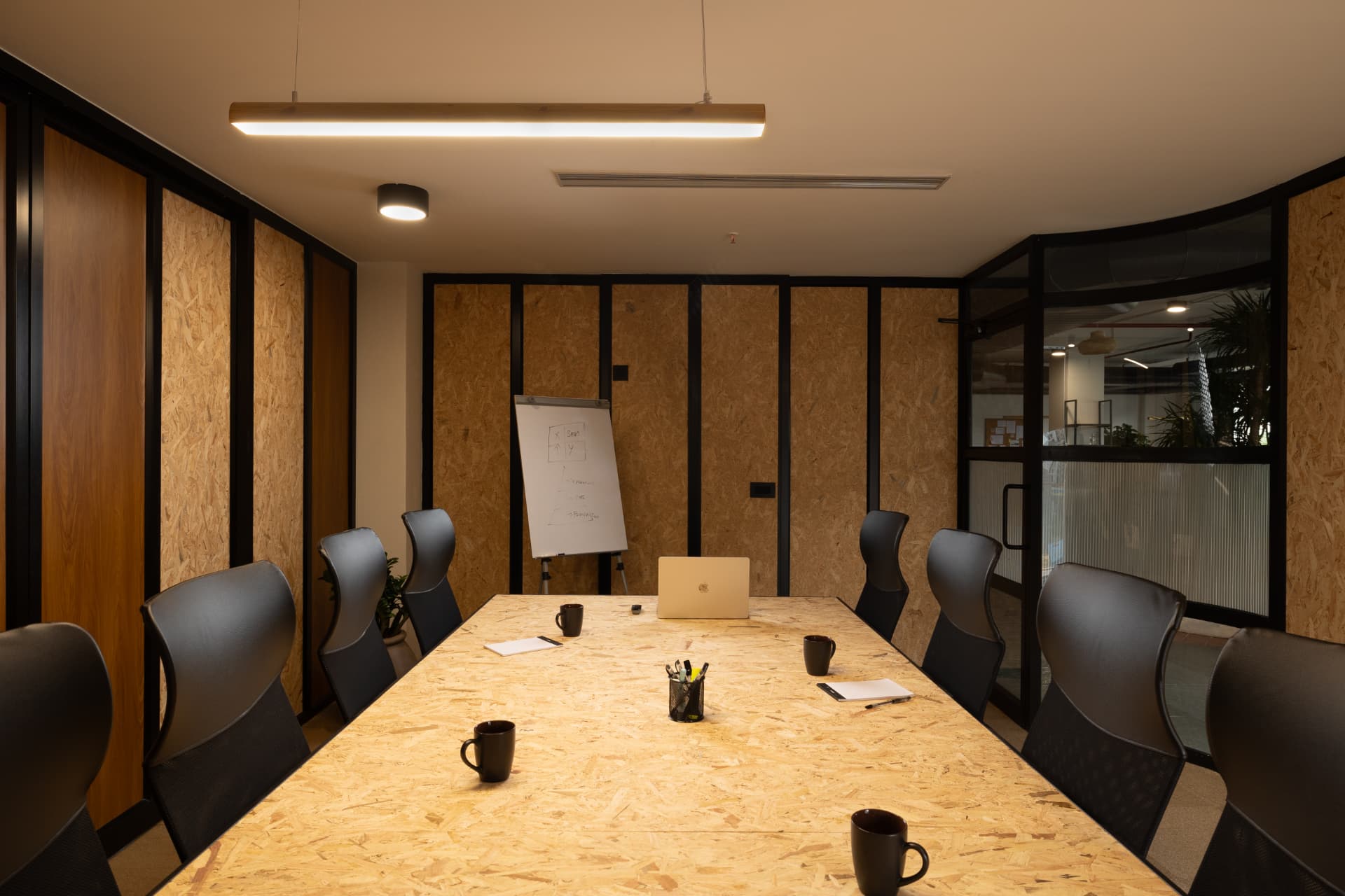 Boardroom at Steadwork ORR | Panathur with a long timber table, black framed glazing and a pendant light