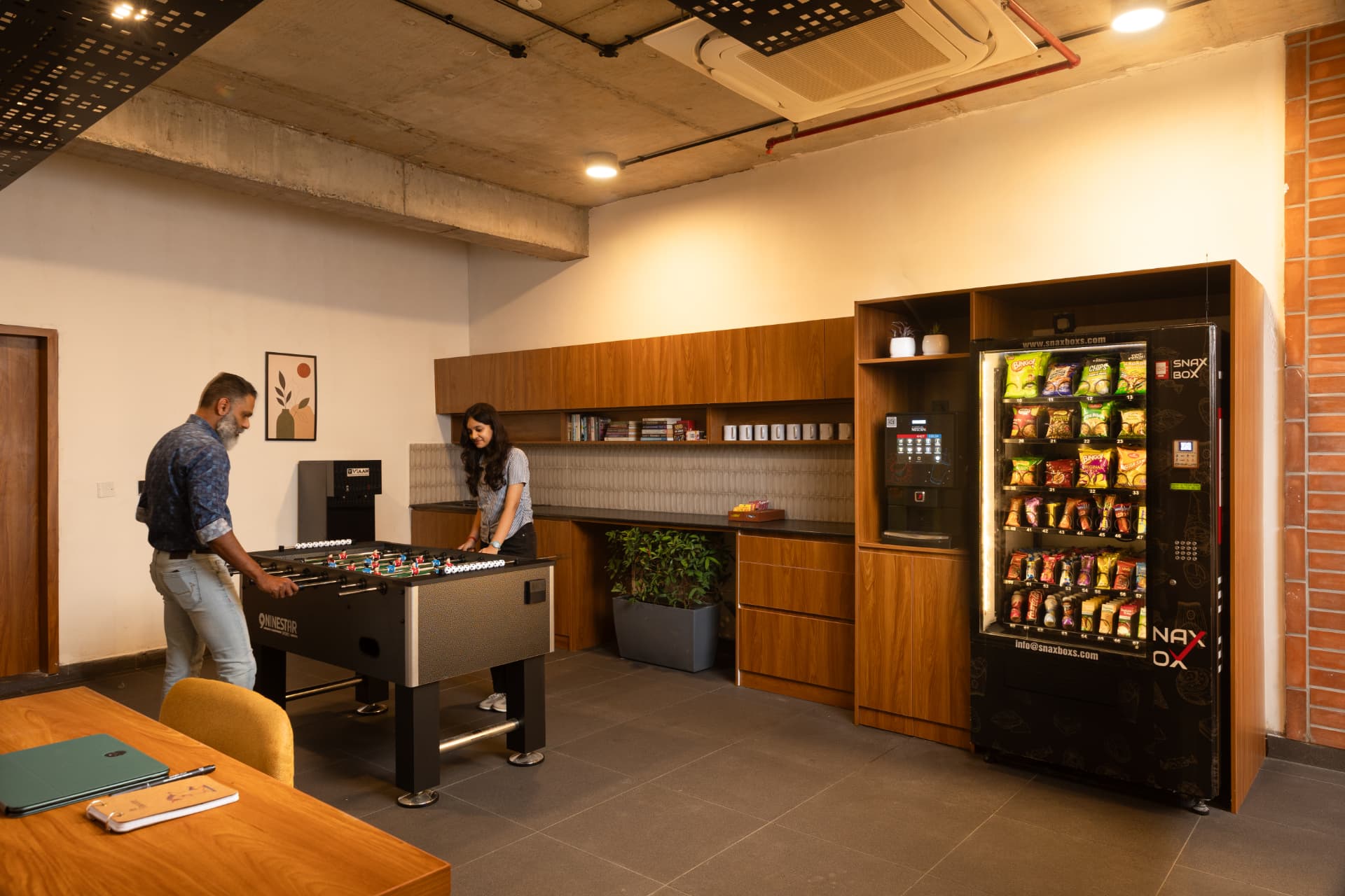 Common area at Steadwork ORR | Panathur with a foosball table, pantry counter and vending machine